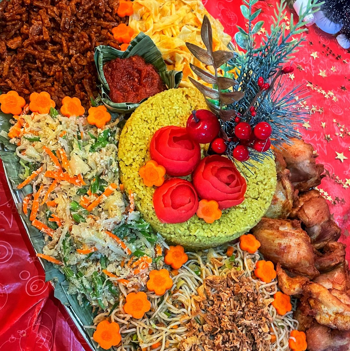Feestelijke nasi kuning met urap, kip, mie en sambal op een bananenblad